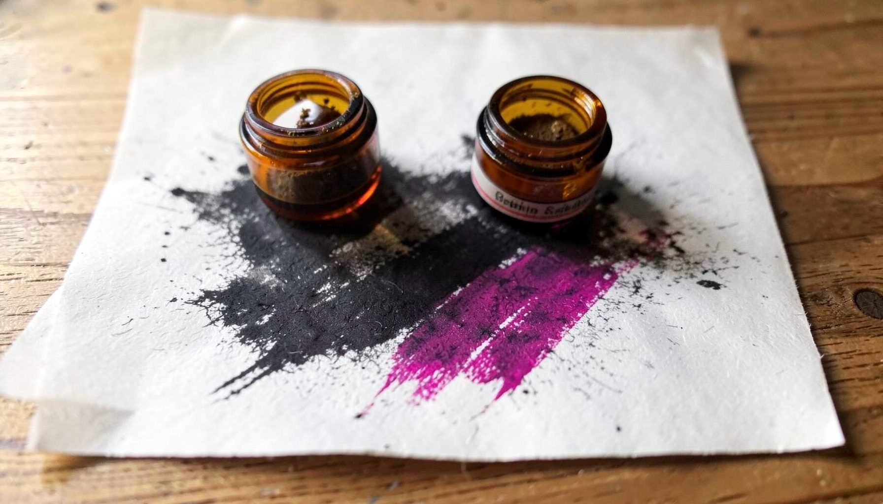 Small amber glass jars of cannabis concentrate on a wooden surface, soft natural light