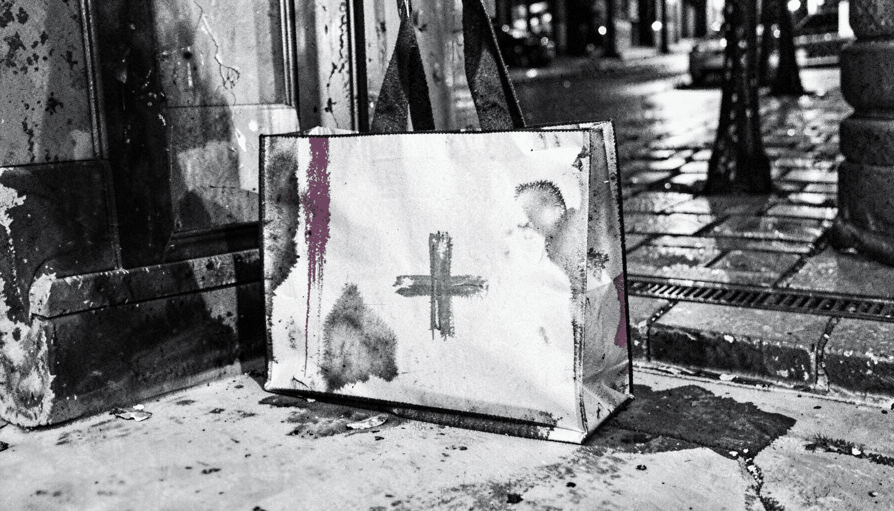 A delivery bag on a doorstep with a subtle green cross logo, evening street scene